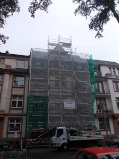 Eingerüstetes mehrgeschossiges Altbaugebäude mit Gerüstnetz