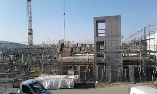 Gerüst an einem Rohbau mit Betontreppenhaus und Baukran
