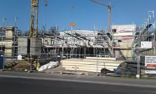 Großbaustelle mit Fassadengerüst, Kran und Transportern