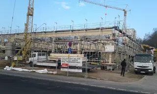 Eingerüsteter Neubau mit Baukran und Gerüstmaterial