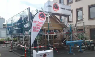 Gerüst mit Werbebanner an einem Holzbau
