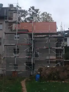 Fassadengerüst an einem Wohnhaus mit Ziegeldach im Garten