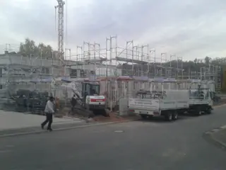 Baustelle mit Fassadengerüst, Bagger und Gerüst-Lkw