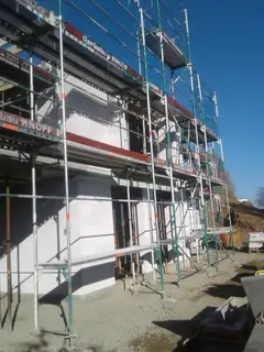 Fassadengerüst an einem weiß verputzten Neubau