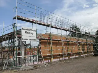 Gerüst mit Bauschild „Gerüstbau Knopp“ an einem Neubau