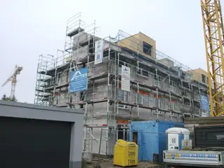 Fassadengerüst an einem Neubau mit Baukran und Baucontainer