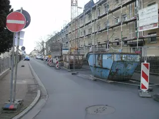 Eingerüstete Häuserzeile in einer Straße mit Absperrung
