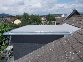 Kaminkopf mit Blechabdeckung auf einem Ziegeldach