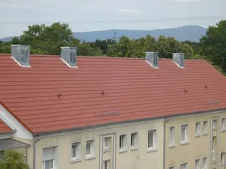 Ziegeldach mit verblechten Kaminköpfen auf einem Wohnblock